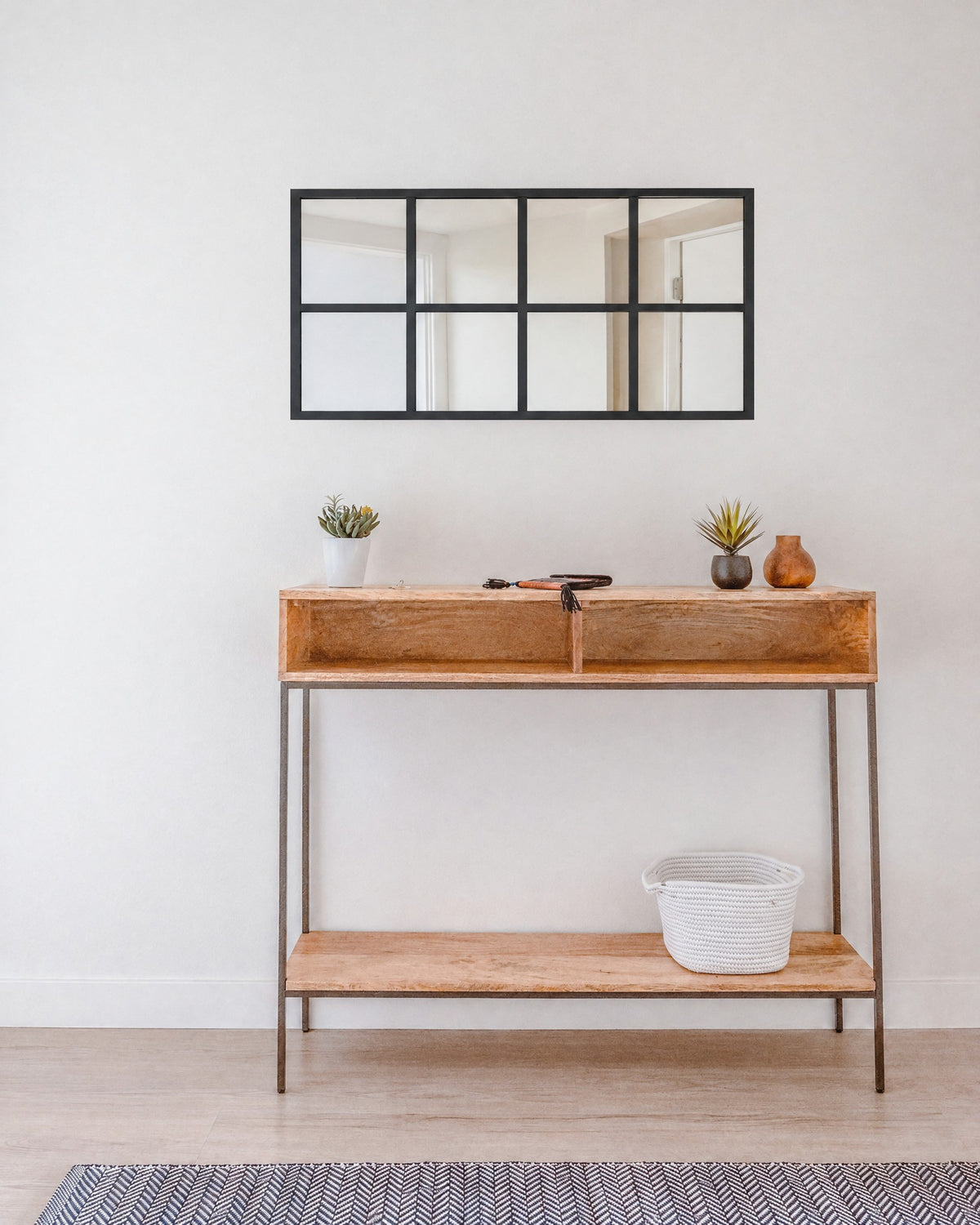 Black window pane wall mirror, 16 x 32 in, hung horizontally above an entry console table to show its size